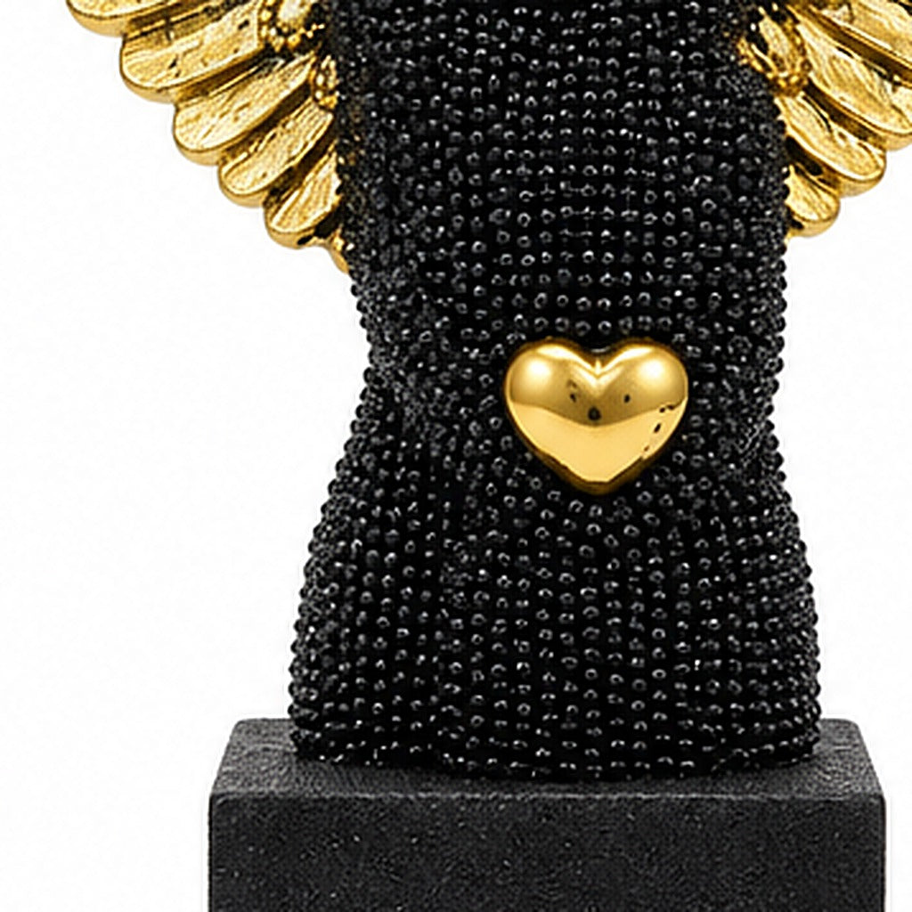 Ángel negro con alas doradas, detalle del corazón