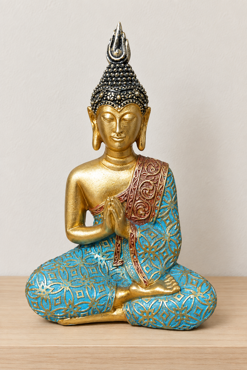 Buda turquesa en oración sobre repisa de madera