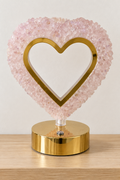 Lámpara de corazón de cuarzo rosa sobre repisa de madera